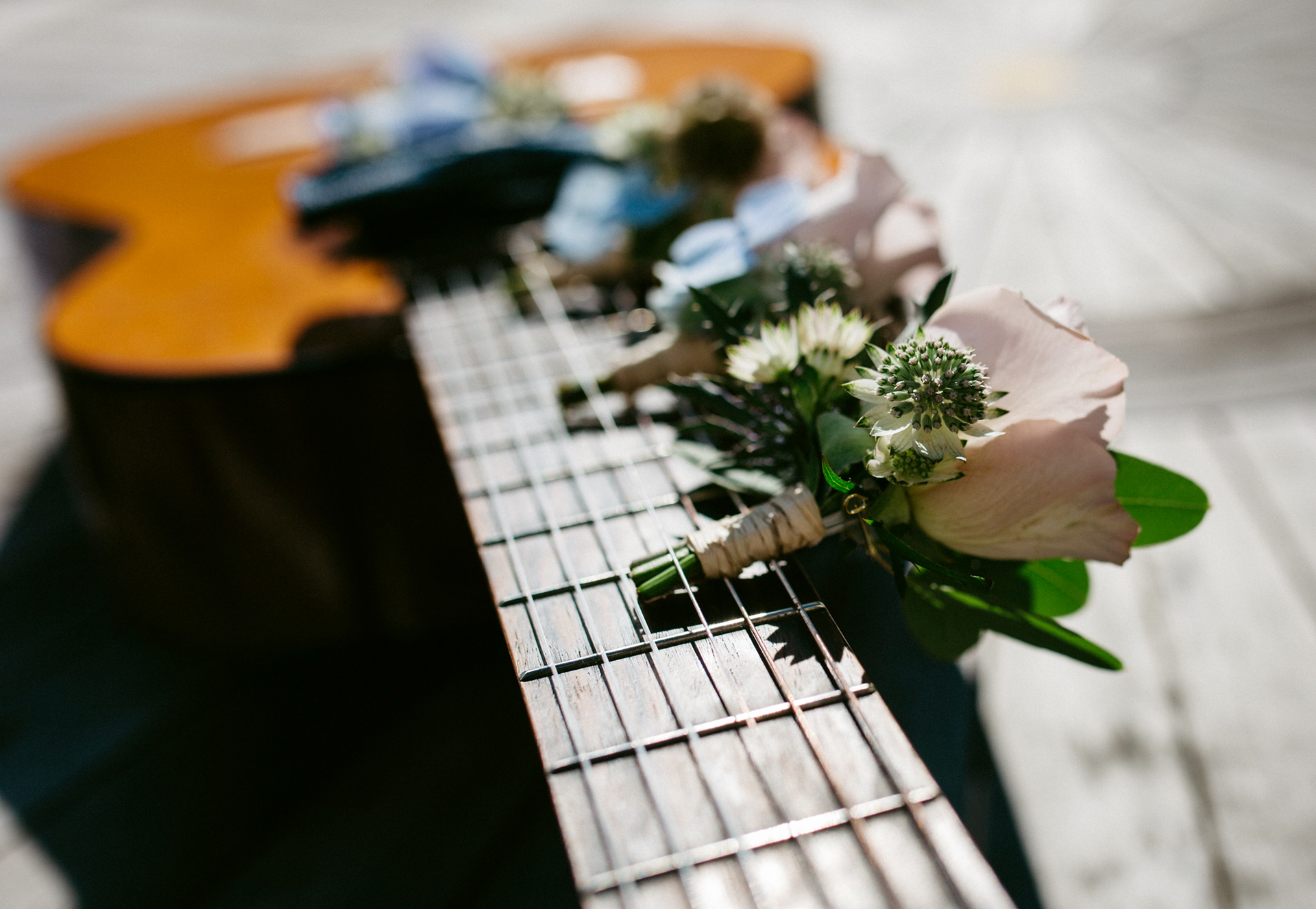 Lähikuva akustisesta kitarasta, jonka kaulalla on pieni kukkakimppu.