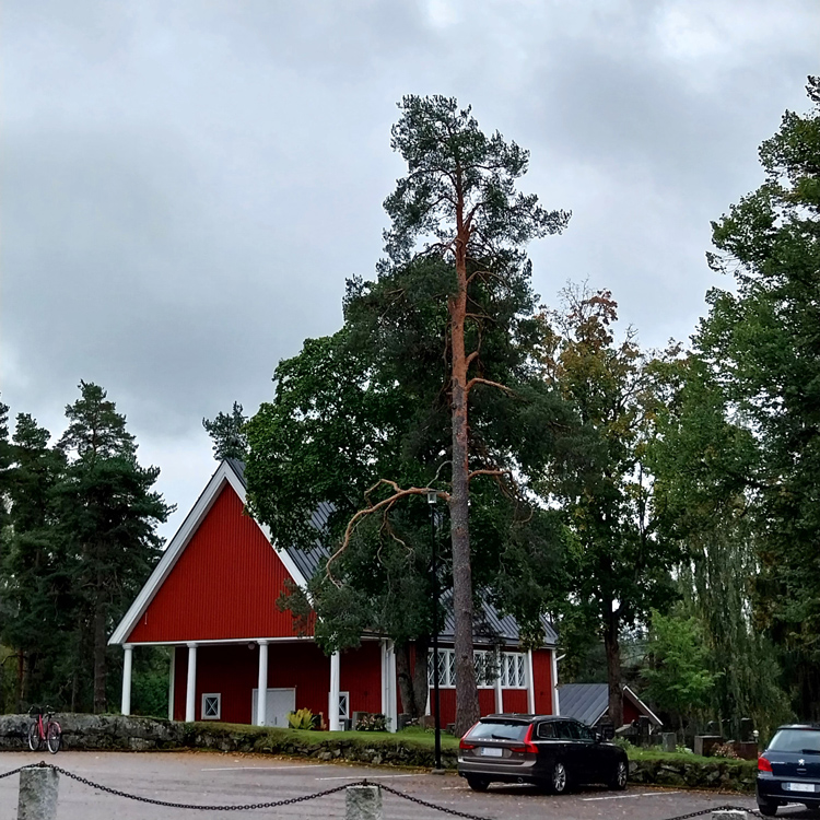 Punaiseksi maalattu Nurmijärven siunauskappeli hautausmaan parkkipaikalta päin kuvattuna.