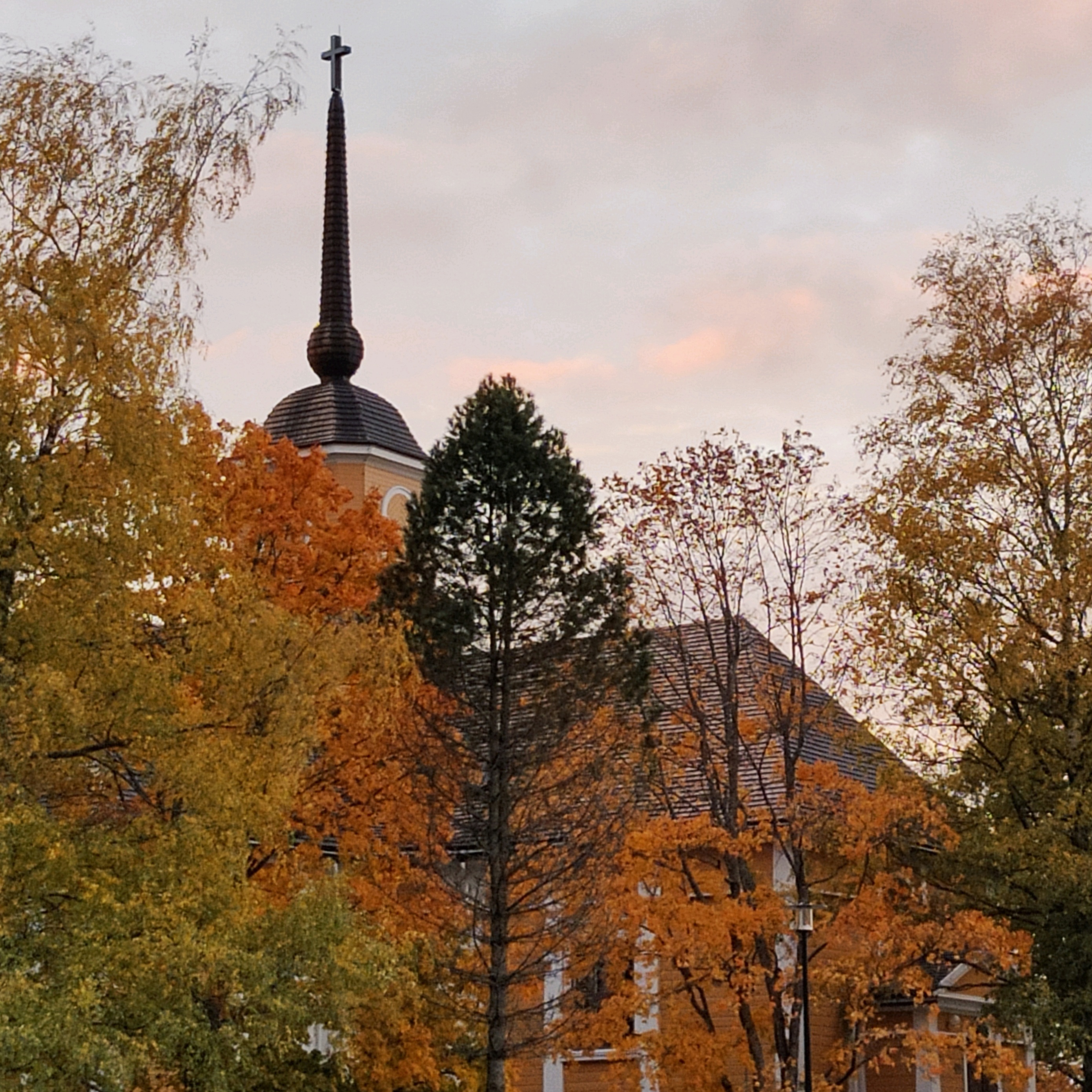 Nurmijärven kirkko syksyllä värikkäiden puiden ympäröimänä.