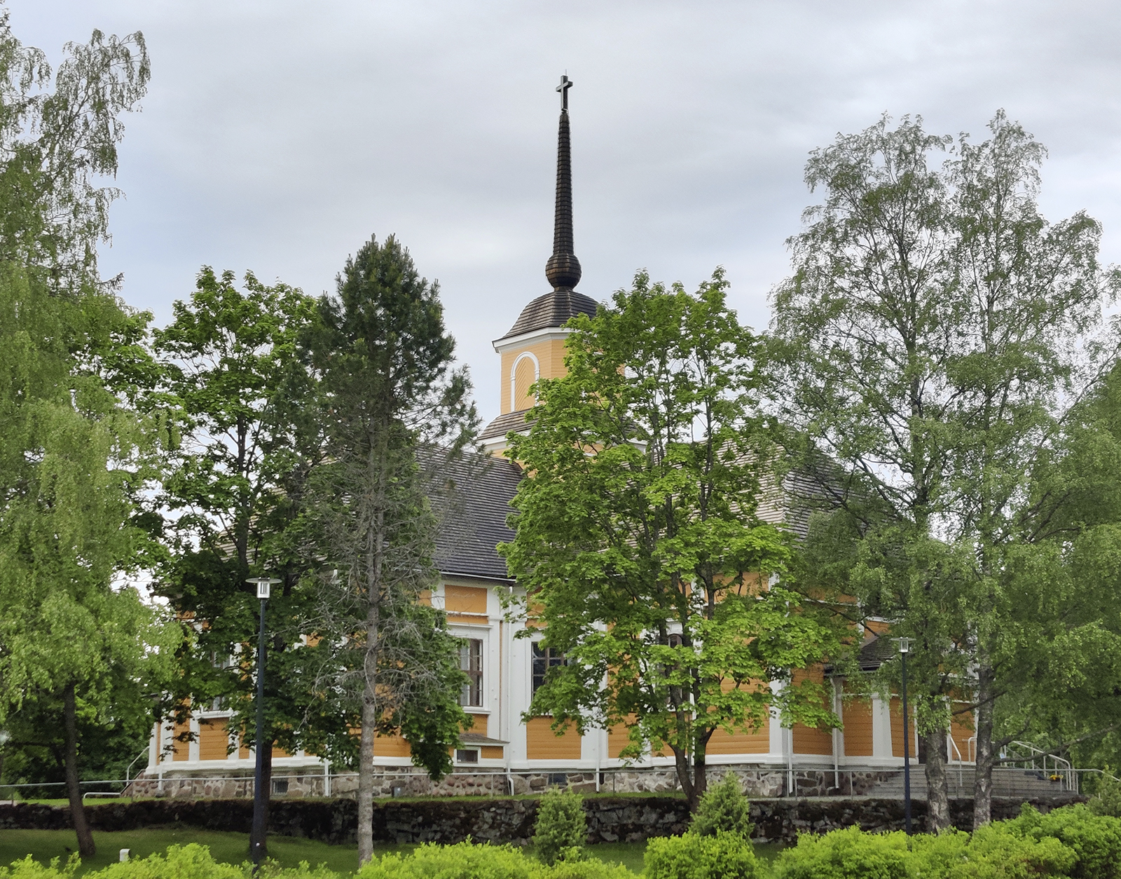 Nurmijärven kirkko sijaitsee lehtipuiden ympäröimänä.