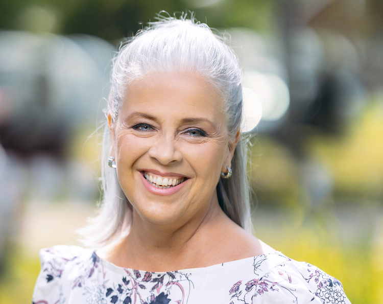 Elina Vettenranta hymyilee kesäisessä ympäristössä.