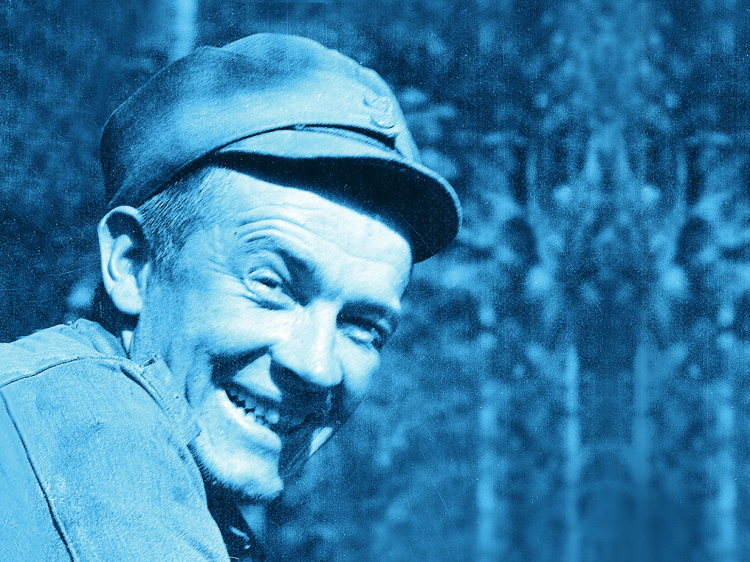 SA-kuva jatkosodan ajalta, jossa naurava sotamies rähjäisissä varusteissa.