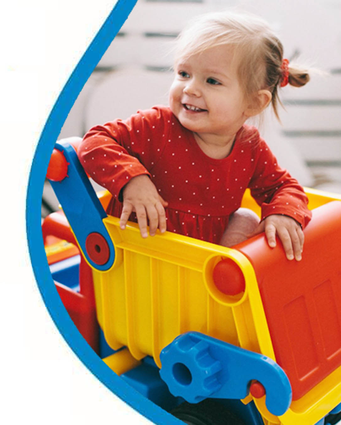 Pieni lapsi istuu leikkiauton kyydissä ja nauraa