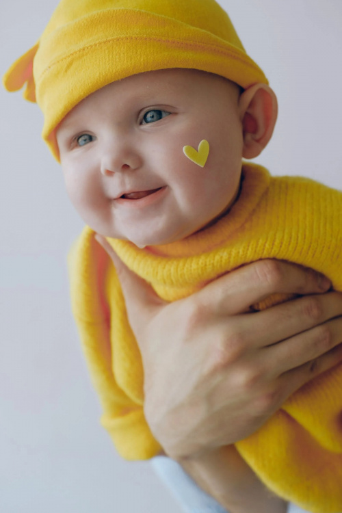 Kuvassa iloinen pieni vauva keltaisessa asussaan