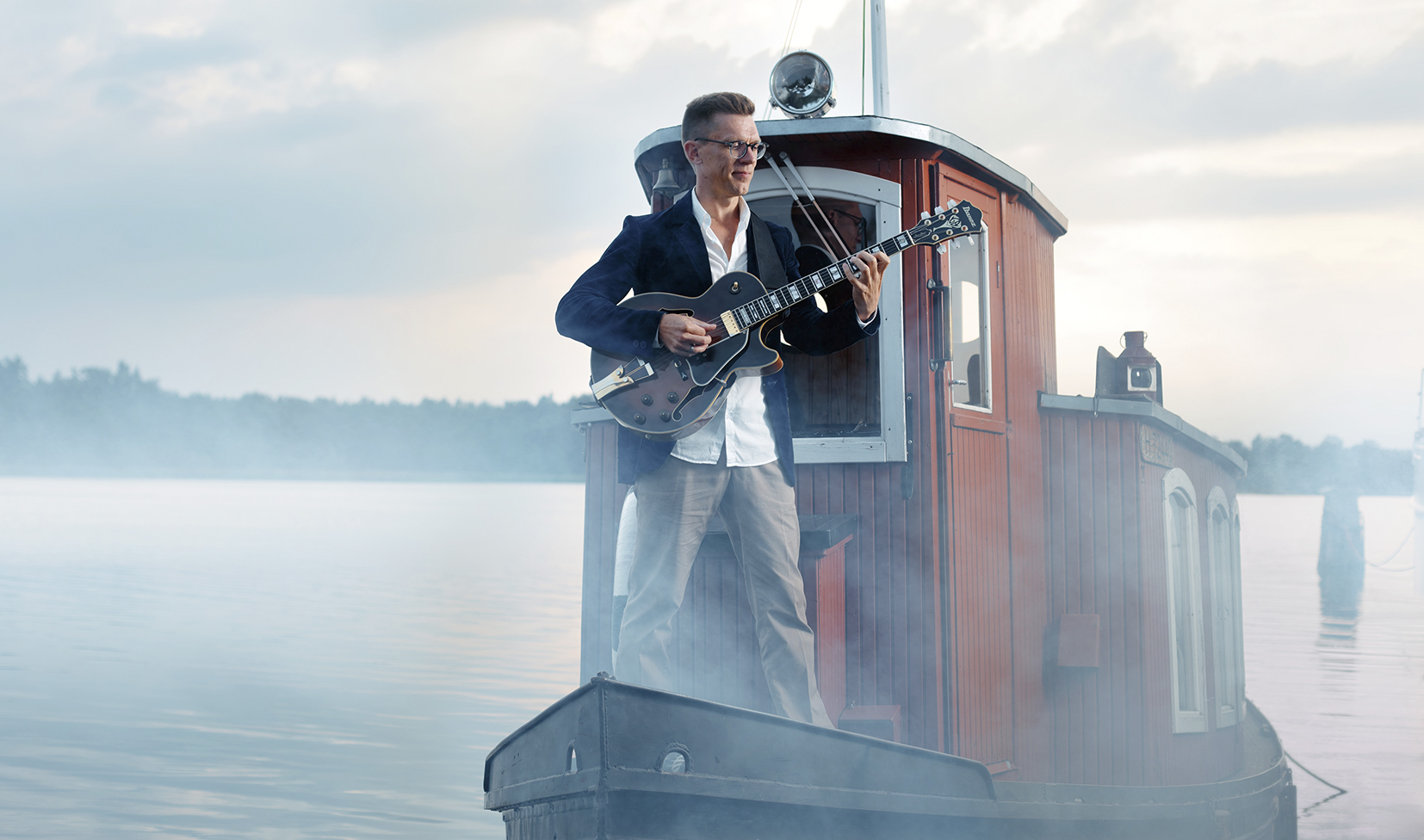 Musiikkia kesäillassa: Freedom Music Mathias Sandberg soittaa kitara kesäillassa pienen hinaajan kannella.