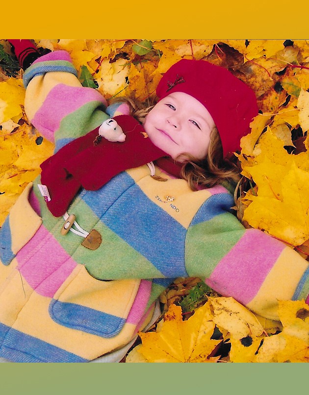 iloinen lapsi makaa värikkäässä lehtikasassa