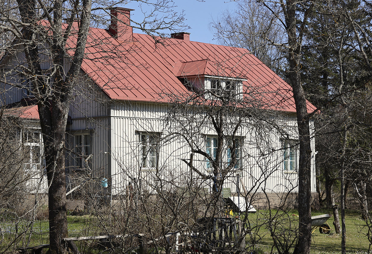 Kaksikerroksisen talon pihalla kasvaa omenapuita.